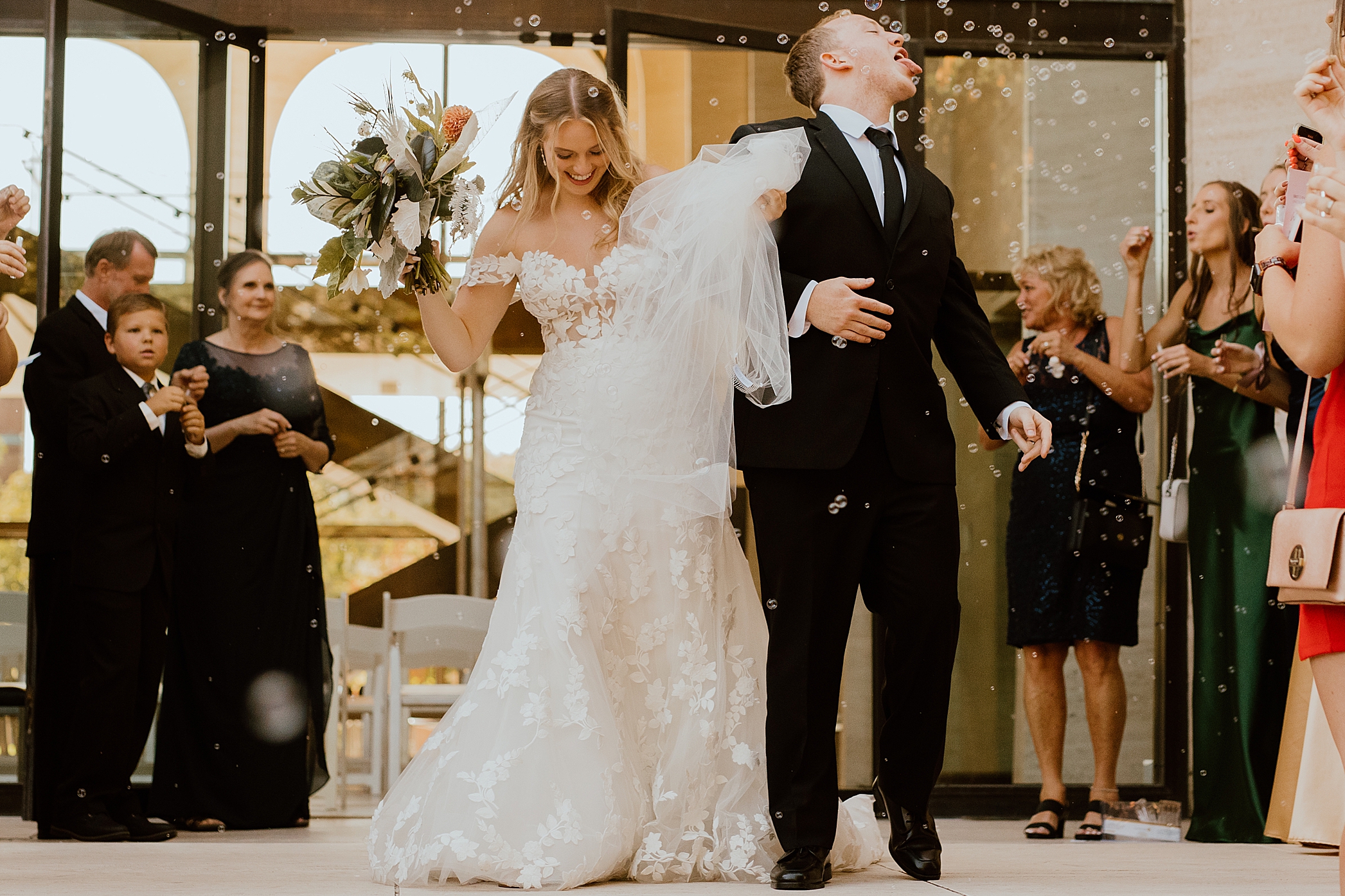 happy bride and groom leaving their wedding groom is catching a bubble in his mouth a must do