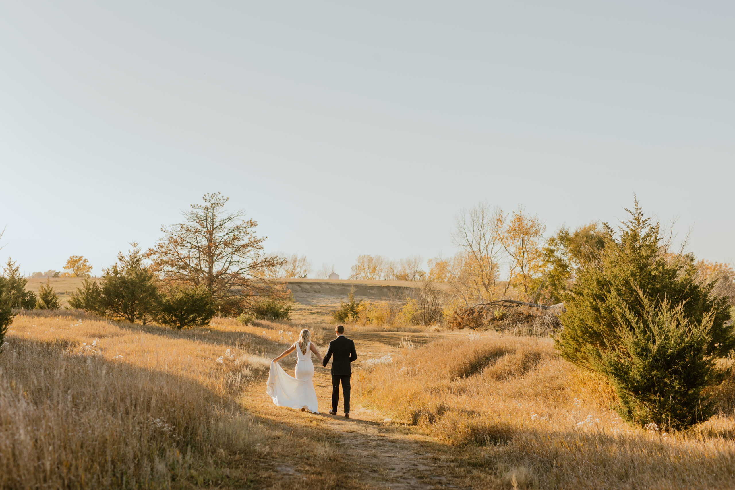bride and groom walking down a dirt path into the distance as the wedding photographer captures their wedding day