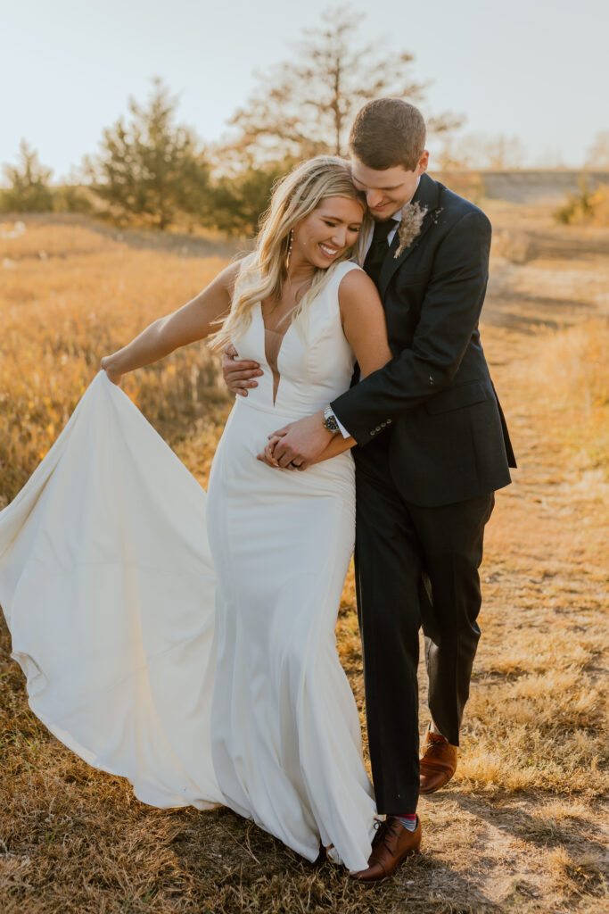 bride and groom standing snuggle in outdoor setting